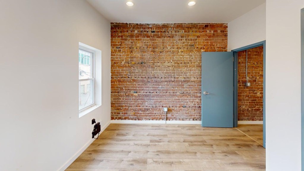 A room with a brick wall and a blue door.
