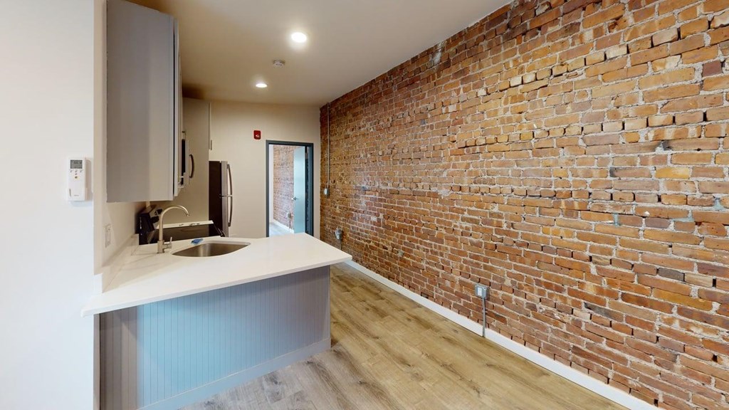 A kitchen with a brick wall and a white counter.