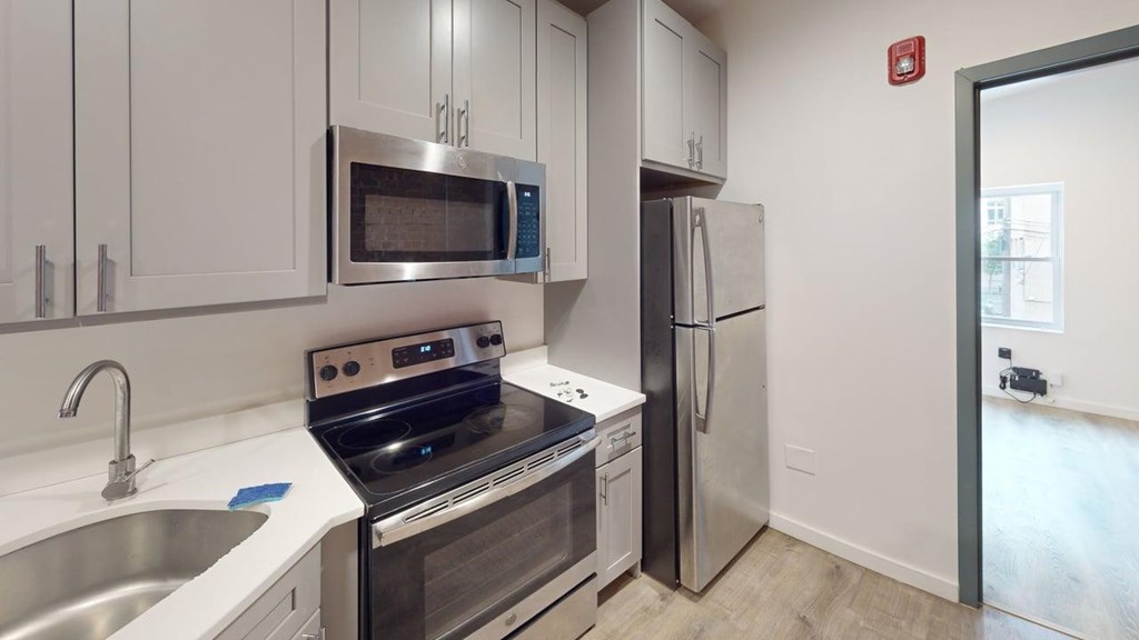 A modern kitchen with a stove, microwave, and refrigerator.