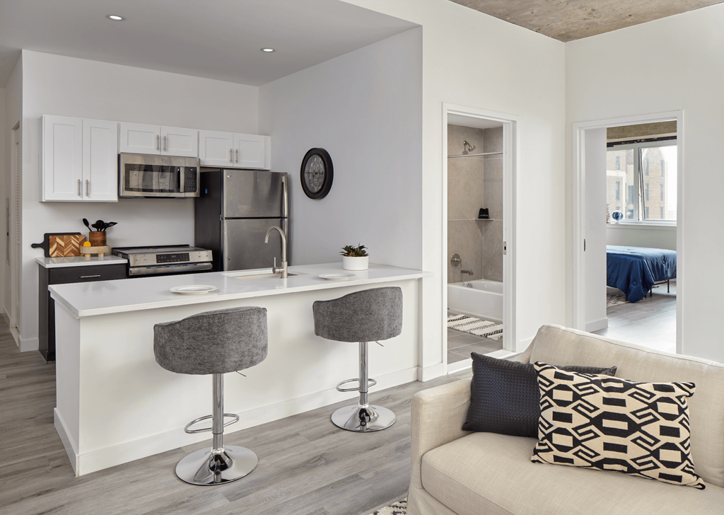 A modern kitchen with white cabinets and a bar area.