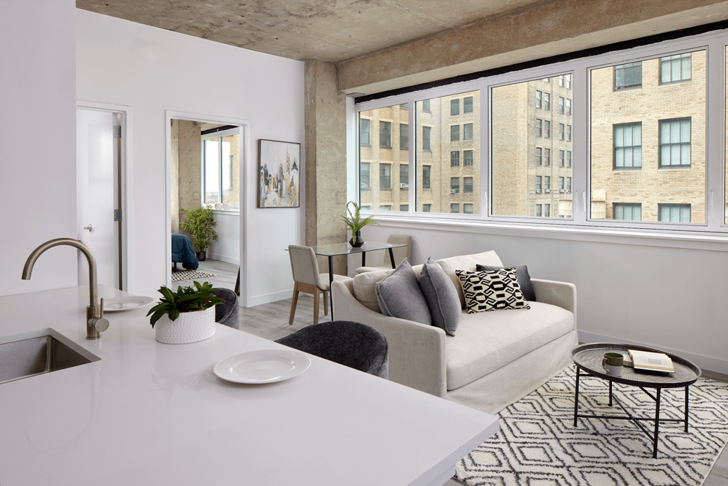 A modern kitchen with a white countertop and a large window overlooking a cityscape.