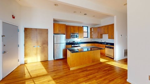 a large kitchen with wooden floors and a stainless steel refrigerator