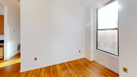 a living room with white walls and wood floors and a window