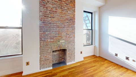 a living room with a brick fireplace and a wooden floor