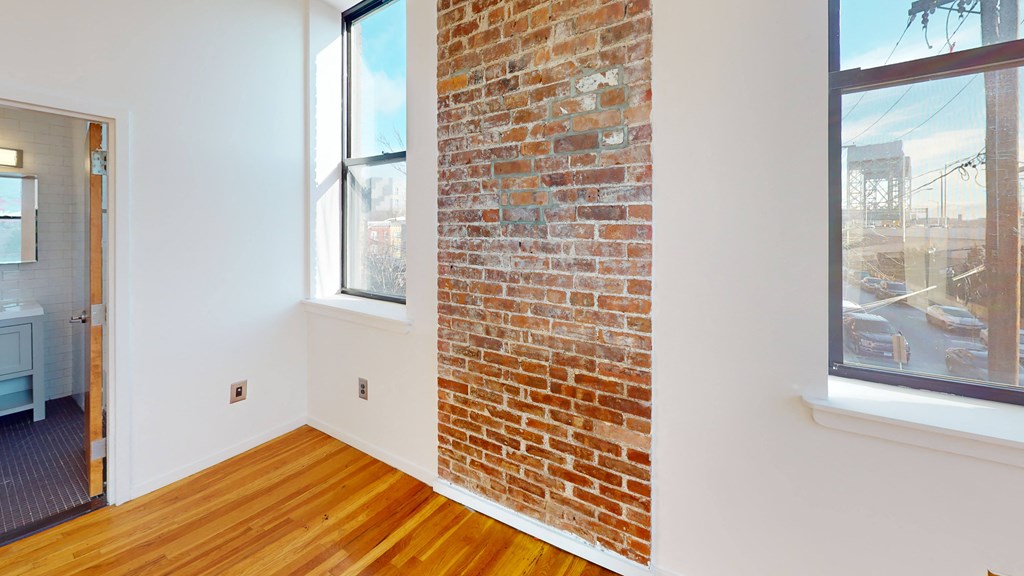 a living room with a brick wall and wood floors