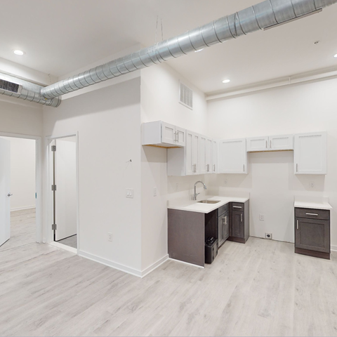 A kitchen with white cabinets and a grey floor.