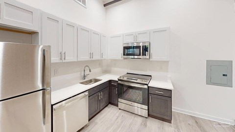 A kitchen with a stainless steel refrigerator, microwave, oven, and sink.