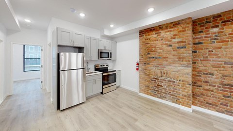 a kitchen with a white refrigerator freezer next to a brick wall