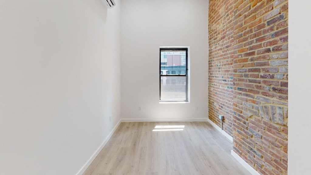 an empty room with a large window and a brick wall