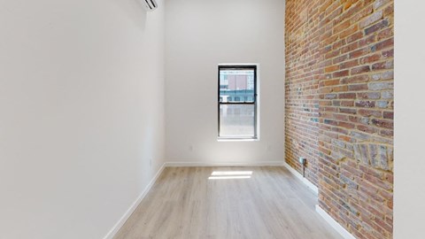 an empty room with a large window and a brick wall