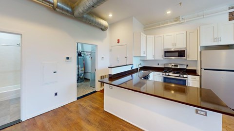 A kitchen with white cabinets and a wooden counter top.