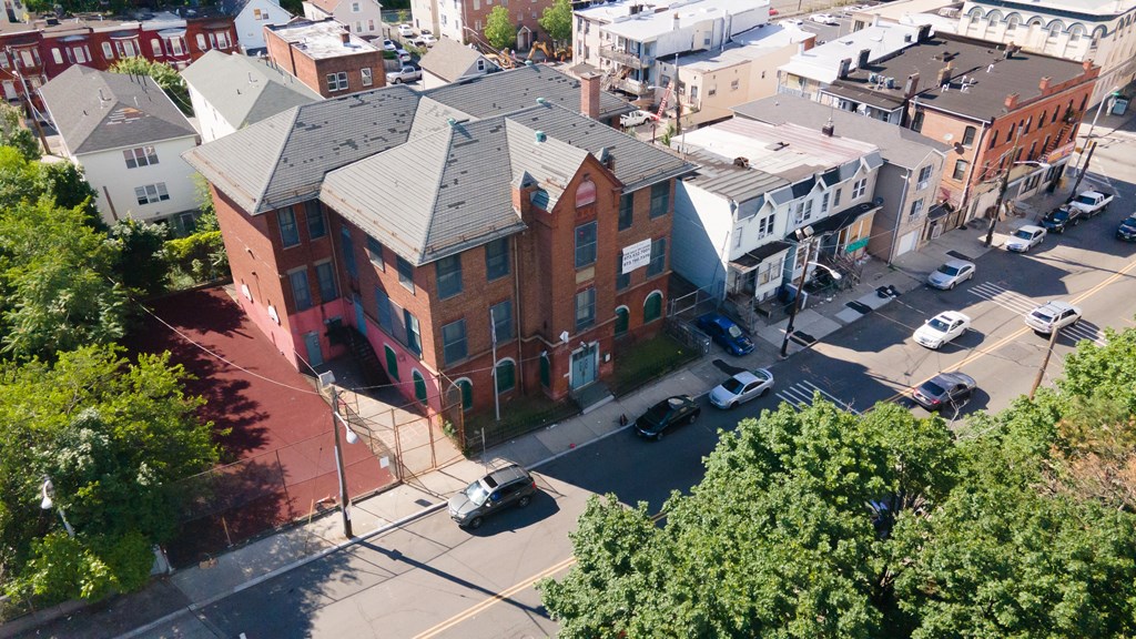 A large red brick building sits in the middle of a city intersection.