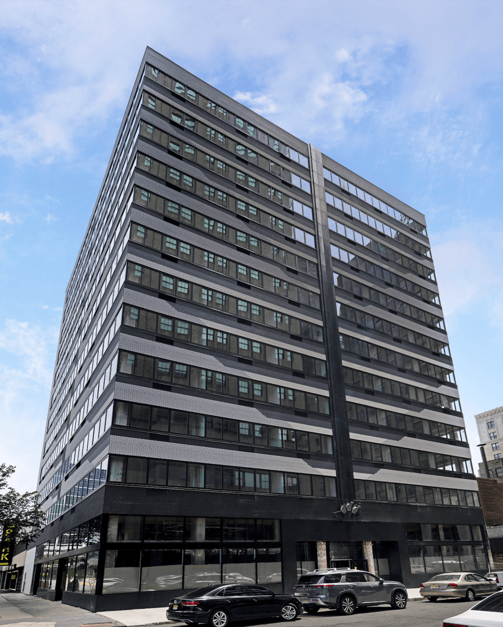 A tall building with a black facade and cars parked in front.