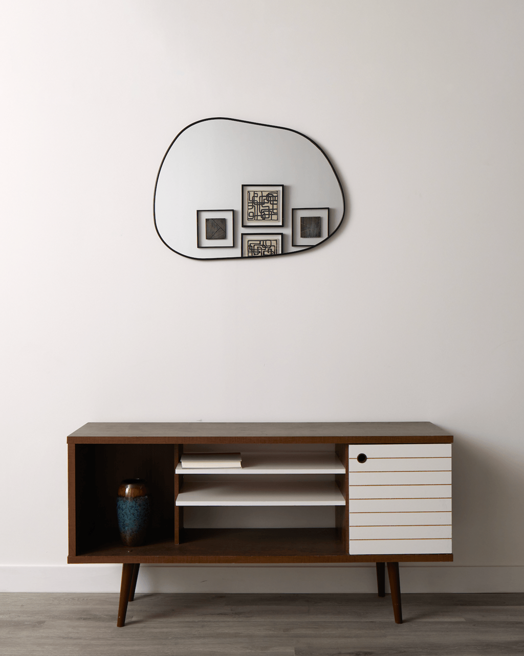A wooden cabinet with a mirror above it.