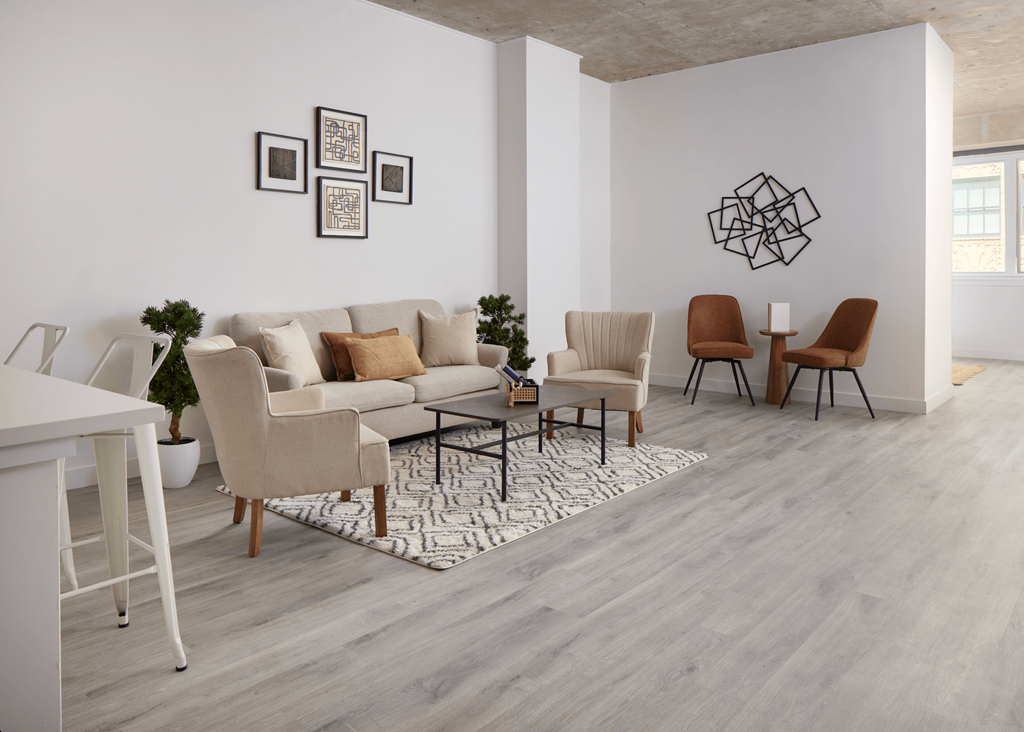 A living room with a grey sofa, two chairs and a table.