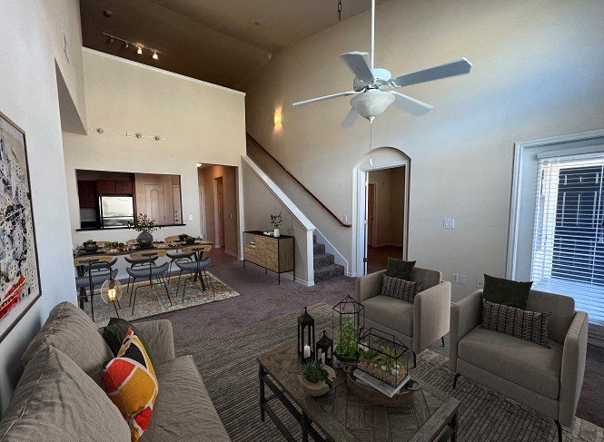 a living room with a ceiling fan and couches