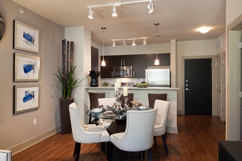 A modern dining room with a glass table and white chairs.