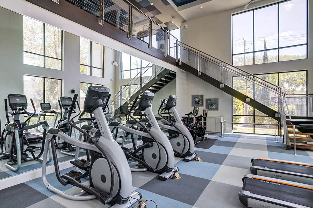 a gym with cardio bikes and a staircase