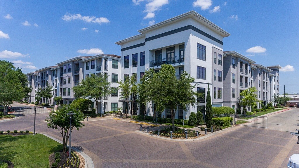 an exterior view of an apartment building with trees and a street