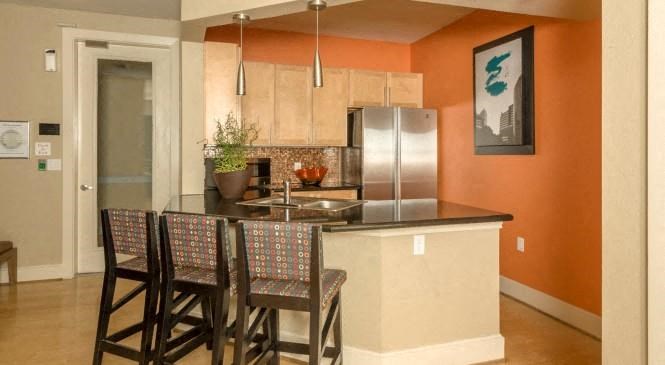 a kitchen with a bar with three chairs