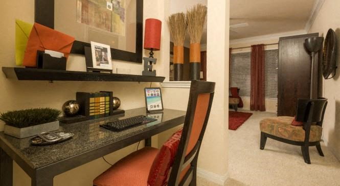a desk with a computer and a chair in a room
