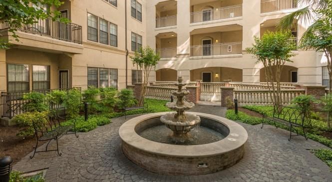 an outdoor courtyard with a fountain in front of an apartment building