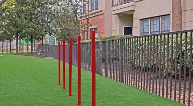 a row of red poles in the grass next to a fence