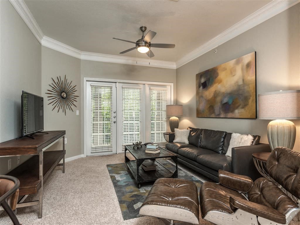 a living room with leather furniture and a ceiling fan