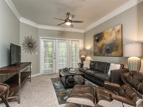 a living room with leather furniture and a ceiling fan