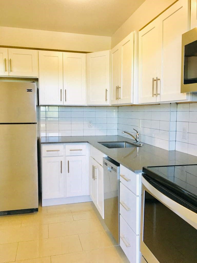 a kitchen with white cabinets and a sink and a refrigerator