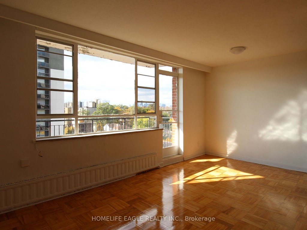 an empty living room with large windows and wooden floors