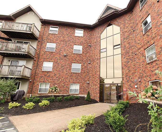 a sidewalk in front of a brick apartment building