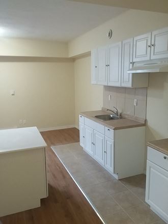 an empty kitchen with white cabinets and a sink
