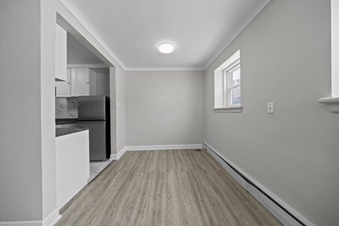 A kitchen with a refrigerator, cabinets, and a window.