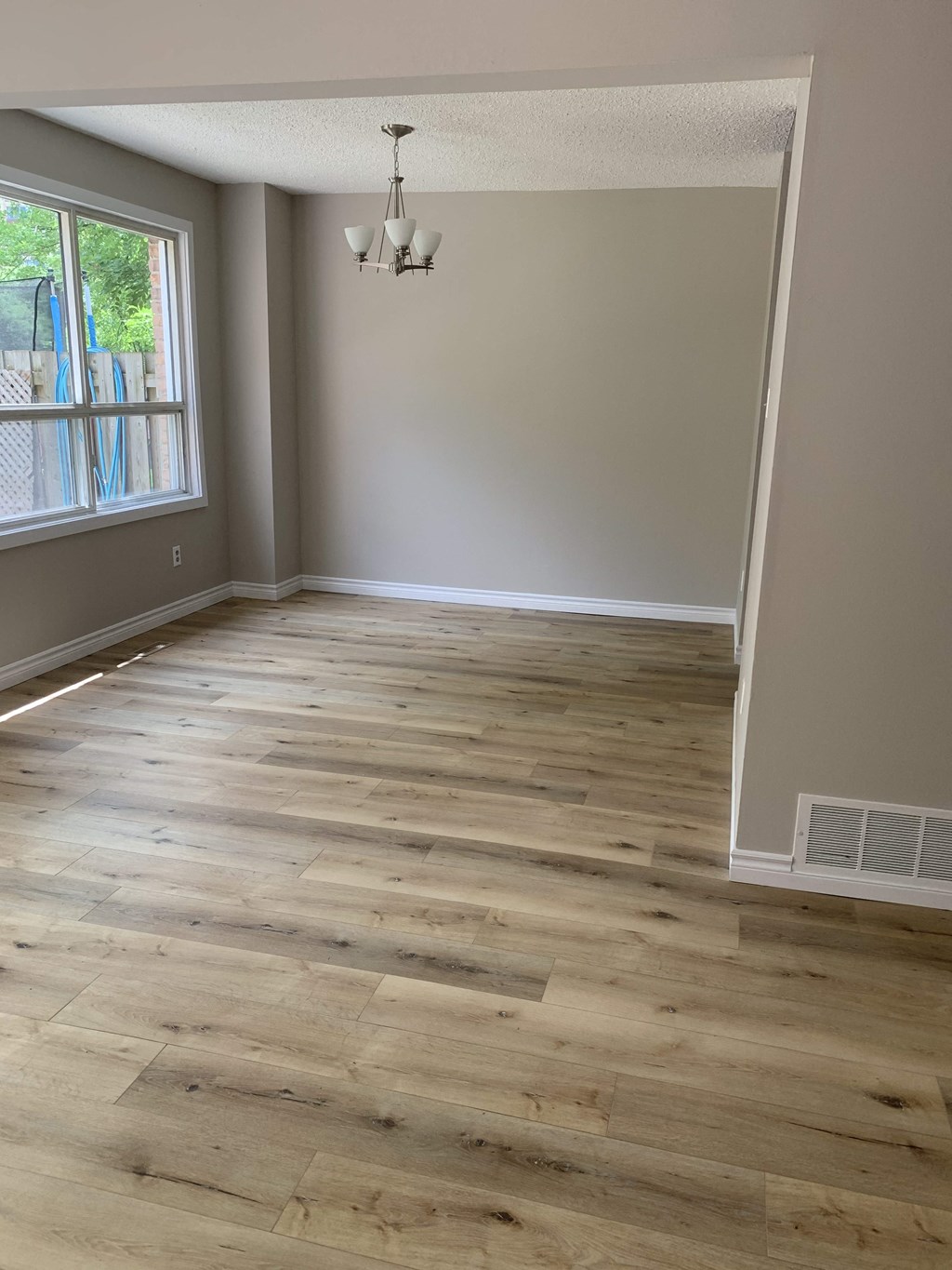 an empty living room with wooden floors and a window