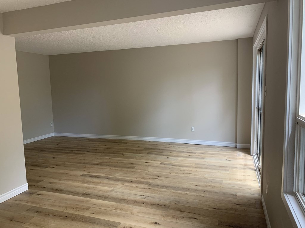 an empty living room with wooden floors and grey walls