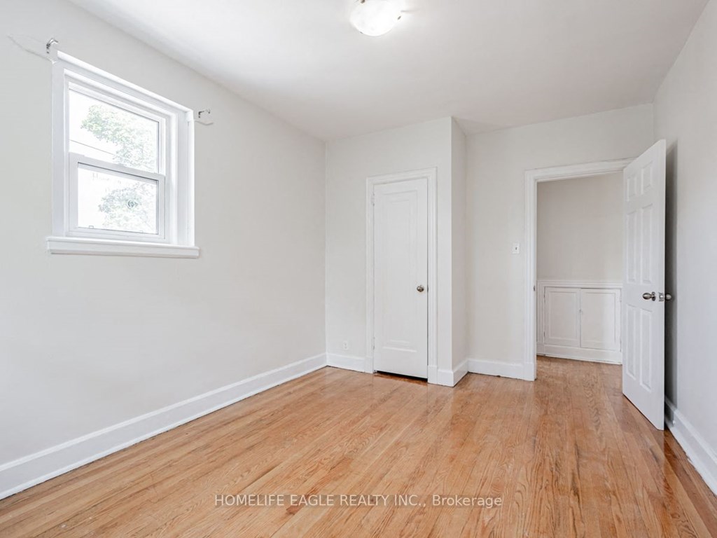 a bedroom with white walls and wood flooring and a window
