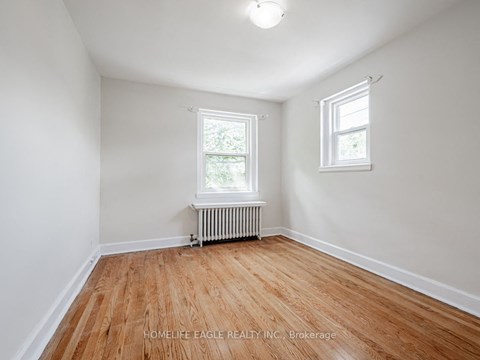 a bedroom with white walls and a wood floor