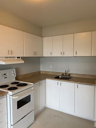 an empty kitchen with white appliances and white cabinets