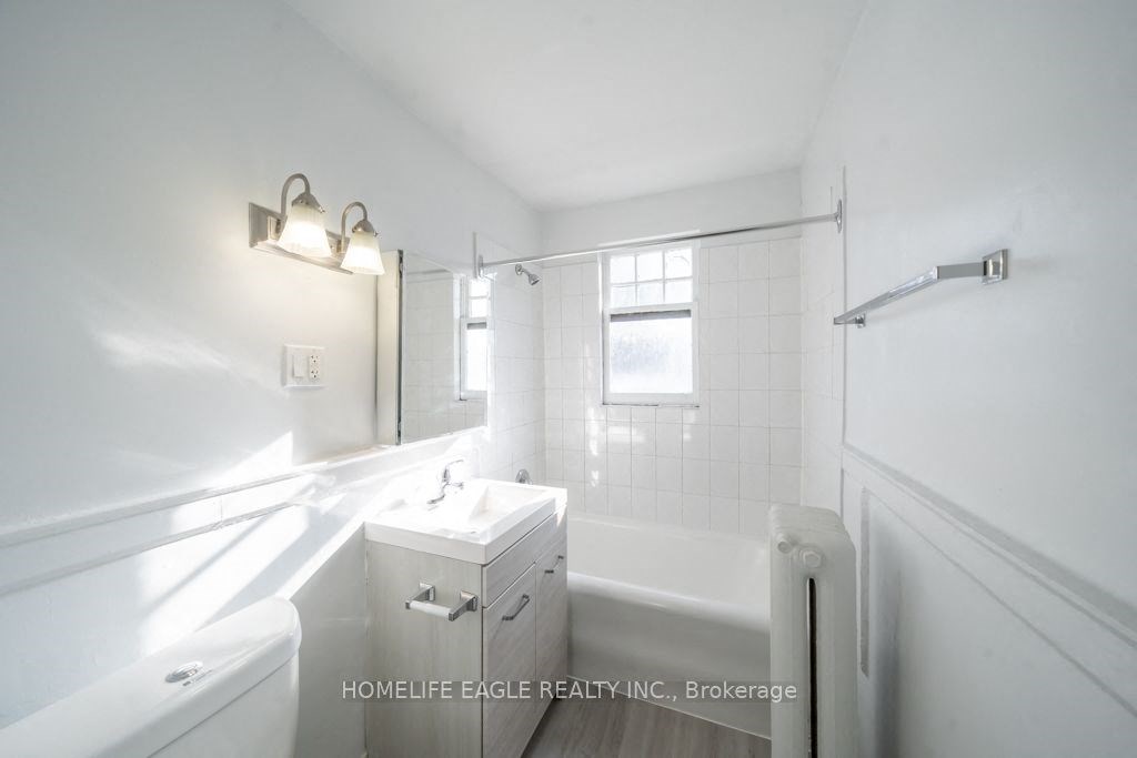 a white bathroom with a tub and a sink and a mirror