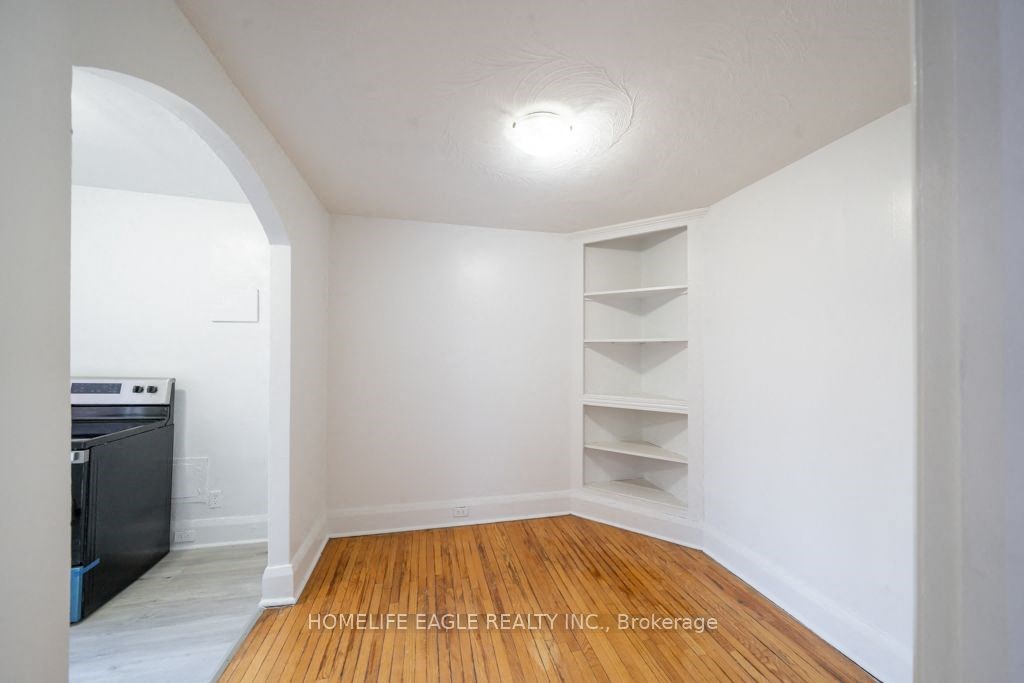 a room with white walls and wooden floors and shelves