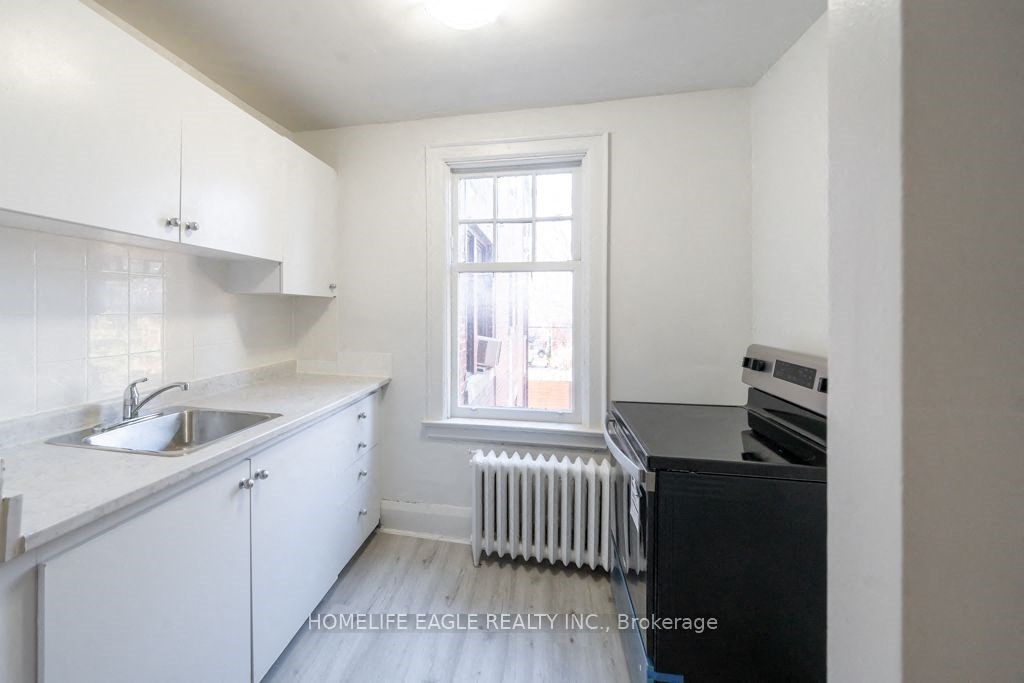 an empty kitchen with white cabinets and a window