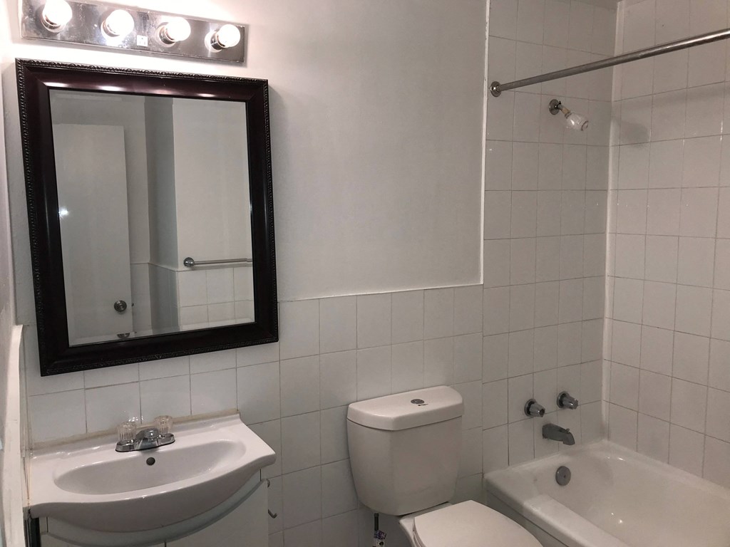 a white bathroom with a mirror and a sink and a toilet