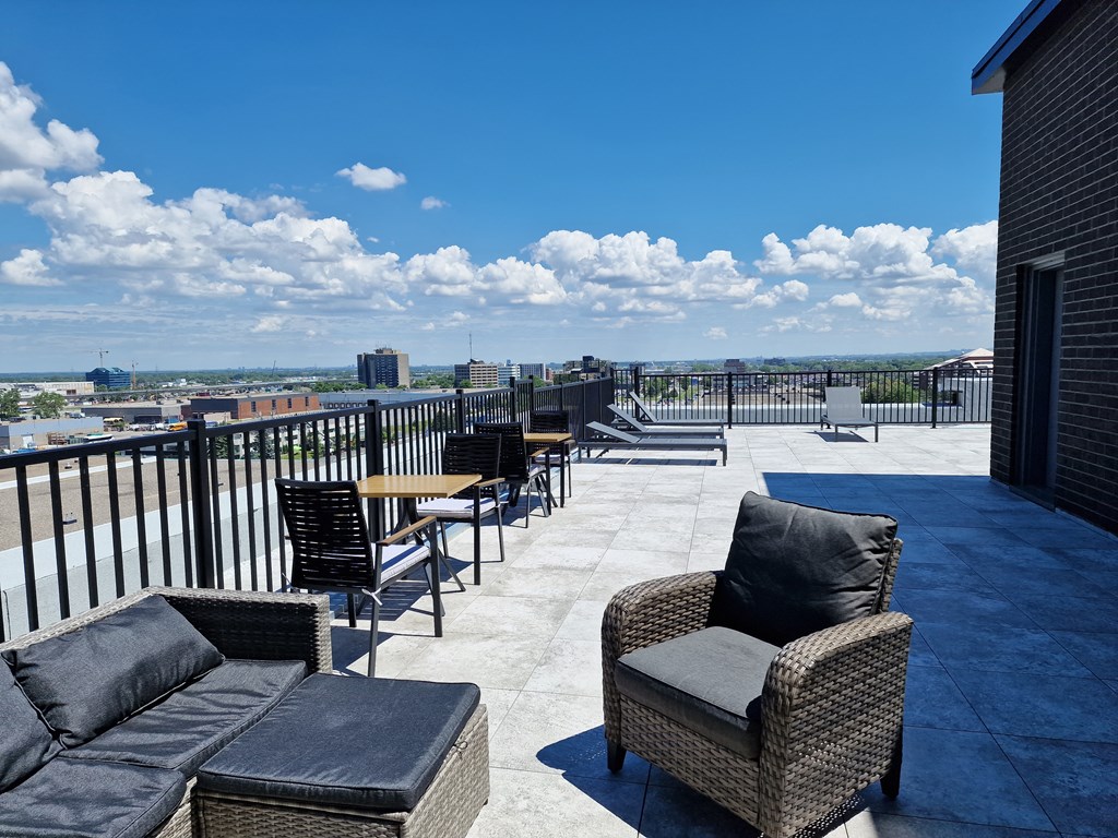 a rooftop patio with chairs and tables and a view of the city