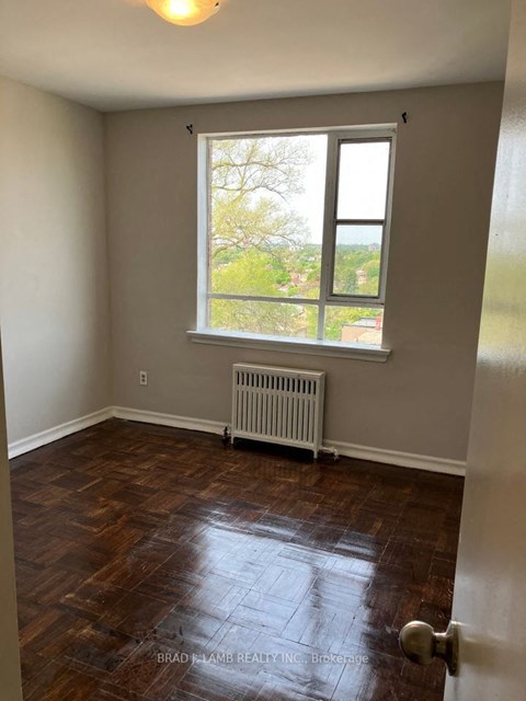 an empty room with a window and wooden floors