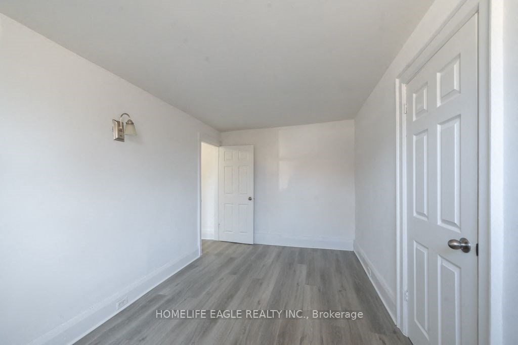 a bedroom with white walls and wood floors and a white door