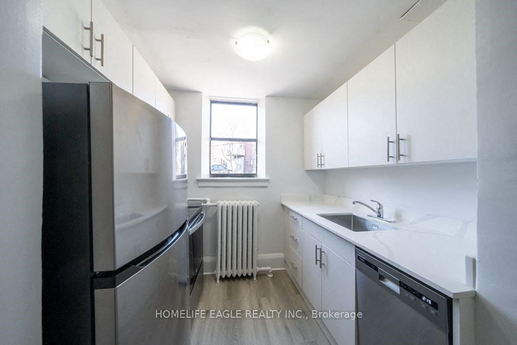 an empty kitchen with white cabinets and a black refrigerator