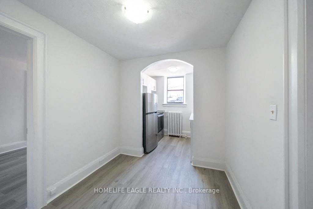 a renovated living room and kitchen with white walls and wood floors