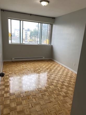 an empty living room with wood flooring and a window
