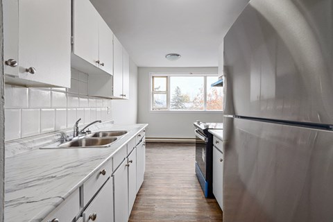 a kitchen with white cabinets and stainless steel appliances and a window